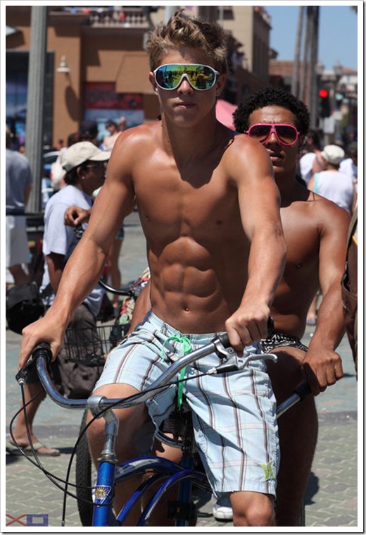 hot boy with abs on a bike at the beach