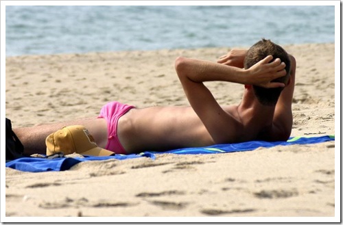 hot boy laying at the beach in a pink speedo